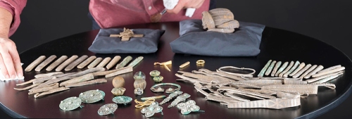 An assemblage from the Galloway Hoard under inspection by Dr Martin Goldberg in the National Museum of SCotland